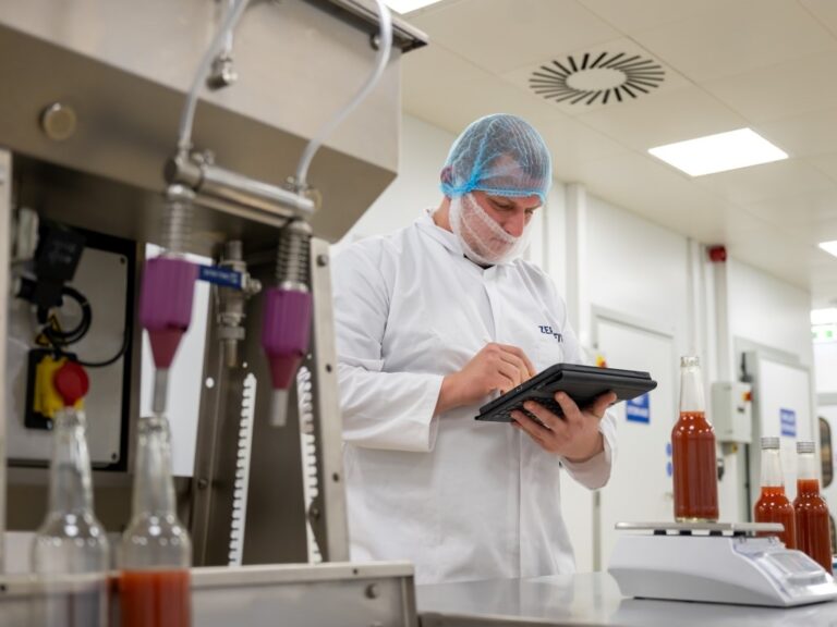 Food technologist logging information on a tablet computer in a food production are