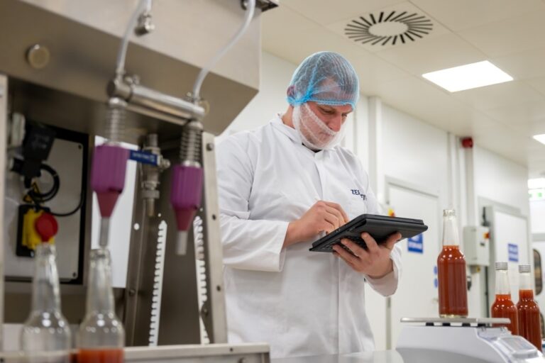 Food technologist logging information on a tablet computer in a food production are