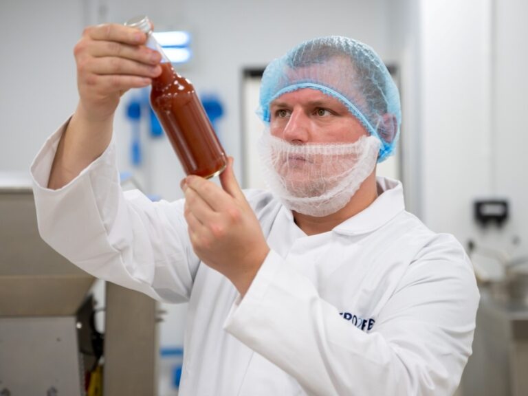 Food production worker inspecting a bottle of sauce