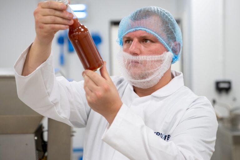 Food production worker inspecting a bottle of sauce