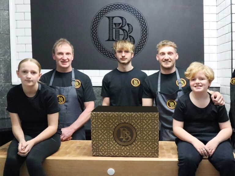 Sam Adams and family posed in front of a Butchery Bocs logo