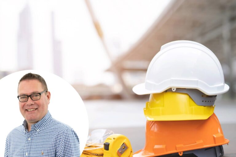 Simon Dawson in front of a background image displaying construction worker helmets